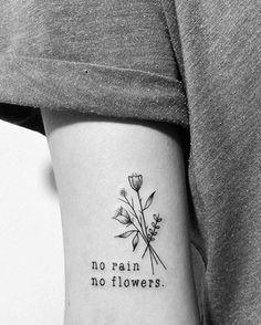 a woman's arm with a small tattoo on it that says no rain, no flowers