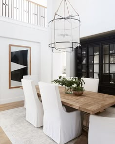 a dining room table with white chairs and a chandelier hanging from the ceiling