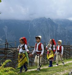 several children in traditional clothing walking up a hill