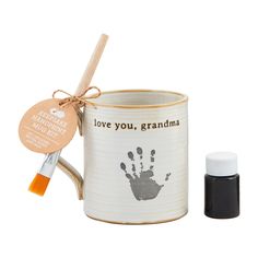 a white mug with a handprint on it next to an orange marker and tag