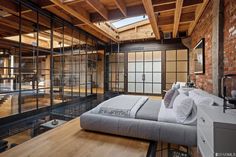 an industrial bedroom with exposed brick and glass walls