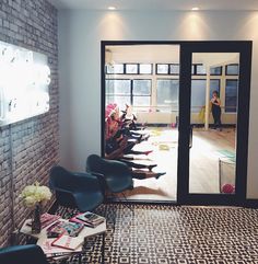 a group of people sitting on chairs in front of a brick wall and glass door