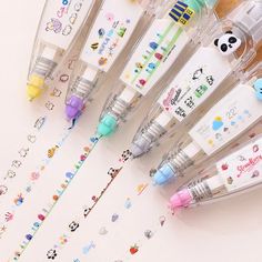 several pens are lined up next to each other on a white surface with cartoon stickers