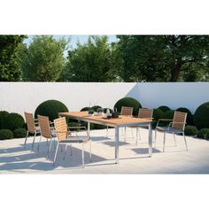 an outdoor dining table and chairs in the middle of a patio with bushes around it