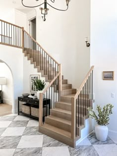 there is a staircase in the middle of this living room with white walls and marble flooring