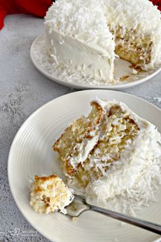 coconut cream poke cake with coconut whipped cream frosting on two white plates, one slice missing