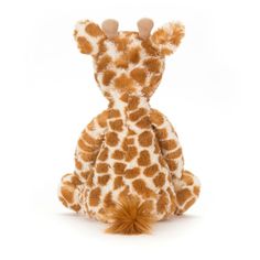 a giraffe stuffed animal sitting on the ground with its head turned to the side