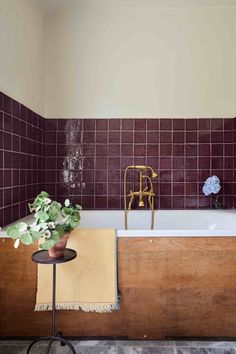 a bath tub sitting next to a table with flowers on it and a towel in front of it