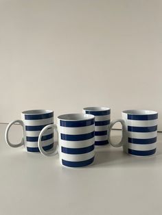 five blue and white striped coffee mugs lined up in a row on a table