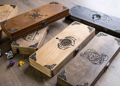 several wooden boxes with designs on them sitting on a table next to small figurines