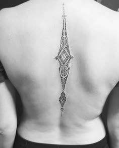 the back of a woman's lower back tattoo with an intricate design on it