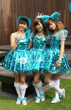 three young women dressed in blue dresses and white socks posing for the camera with their arms around each other