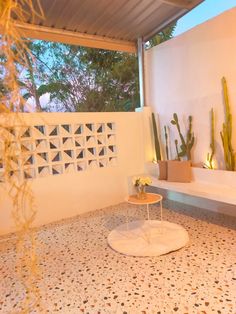 a white bench sitting on top of a tiled floor next to a wall with cacti and succulents