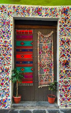 a door with a rug hanging on the side and potted plants next to it