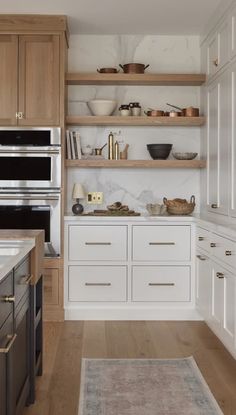 a kitchen with white cabinets and wooden shelves