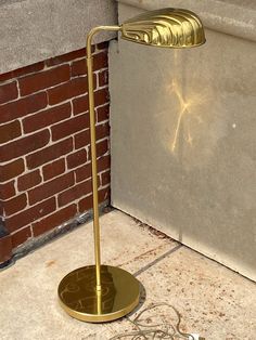 a floor lamp sitting on the ground next to a brick wall