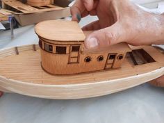 a wooden model of a boat being built by someone's hand on a table