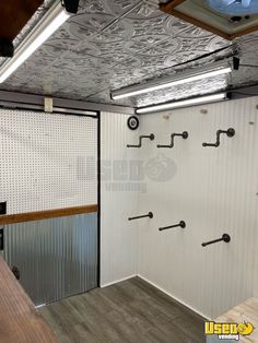 the inside of a storage room with several hooks on the wall and two doors open