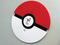 a red and white pokemon ball light switch cover on a wall with a black circle in the center