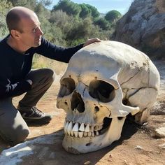 a man kneeling down next to a human skull