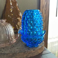 a blue glass vase sitting on top of a wooden table