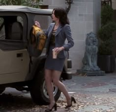 a woman standing next to a car with a jacket hanging out of it's door