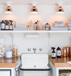 a white kitchen sink sitting under three lights next to a microwave and toaster oven