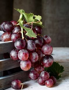 a bunch of grapes sitting on top of a wooden crate