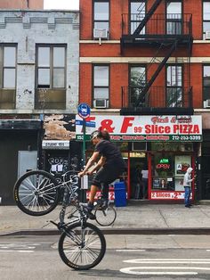 a man riding a bike down the middle of a street next to tall brick buildings