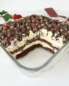 a chocolate cake with white frosting and cherries on top is in a glass dish