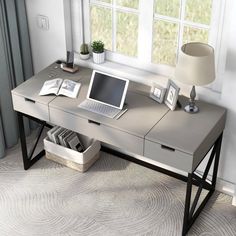 a laptop computer sitting on top of a wooden desk next to a lamp and window