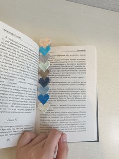 a person is holding an open book with several hearts on it and the pages have been stitched together