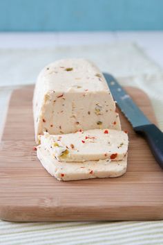 a block of cake sitting on top of a wooden cutting board next to a knife