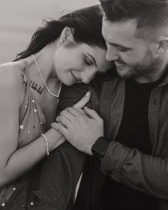 black and white photograph of a couple embracing each other in front of the ocean with pearls on their necklaces