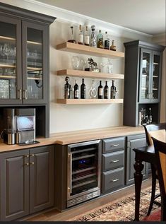 a kitchen with gray cabinets and wine glasses on the shelves