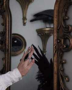 a woman's hand with black nail polish on her nails in front of a mirror