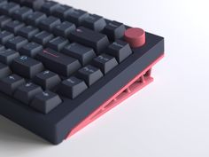 a computer keyboard sitting on top of a white table next to a red mouse pad