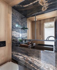 a modern bathroom with marble counter tops and wood paneling on the walls, along with a white toilet