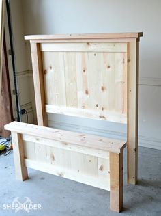 a wooden bed frame sitting on top of a floor next to a pile of wood