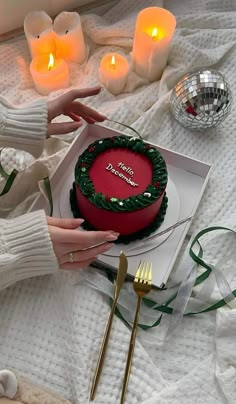 a woman holding a knife and fork over a cake on a table with candles in the background