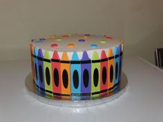 a multicolored cake with white frosting on a table