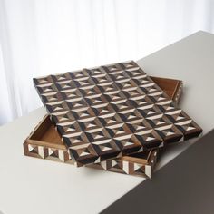 two wooden boxes sitting on top of a white table next to a curtained window