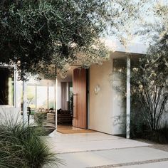 an entrance to a house with trees in the front and side doors on both sides