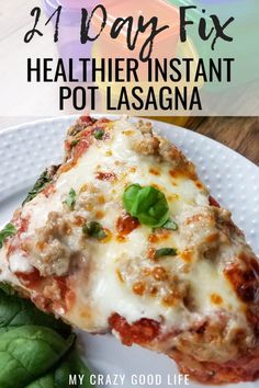 a white plate topped with lasagna covered in cheese and sauce next to spinach leaves