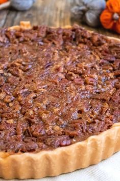 a pecan pie sitting on top of a wooden table next to some pumpkins