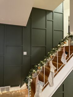 christmas stockings are hanging on the banisters in this home decorated with garland and lights