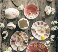 several bowls and plates with flowers painted on them sitting on a wooden table next to each other