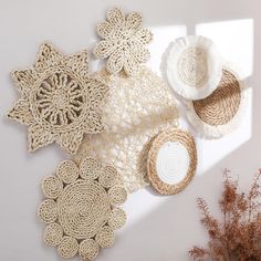 crocheted doily and straw hats are arranged on a white surface next to dried plants