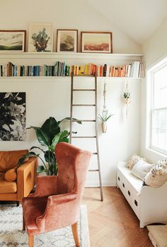 a living room filled with furniture and bookshelves next to a white wall covered in pictures