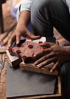 a man is sitting on the floor with his hands on a piece of cake